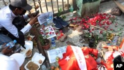 Warga Myanmar memanjatkan doa di lokasi di mana seorang demonstran tewas oleh pasukan keamanan dalam aksi protes di Yangon, Myanmar, Minggu (28/2). 