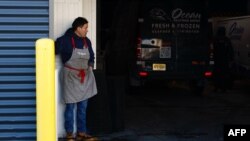 แรงงานยืนที่ด้านหน้าลานจอดรถของร้านค้า ที่เจ้าหน้าที่ตรวจคนเข้าเมืองและศุลกากรเข้าบุกจับแรงงาน ในเมืองนวร์ก รัฐนิวเจอร์ซีย์ วันที่ 24 มกราคม 2025 (ที่มา: AFP)