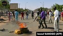 Les partisans de l'opposition nigérienne allument un feu et scandent des slogans alors qu'ils participent à une manifestation dans les rues de Niamey, le 23 février 2021.