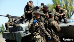 Ukrainian soldiers stand guard beside an armored personnel carrier at a checkpoint in Mariupol, eastern Ukraine, May 7, 2014. 