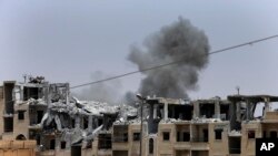 FILE - Asap terlihat dari serangan udara koalisi pada kelompok ISIS, di garis depan di sisi barat Raqqa, timur laut Suriah, 17 Juli 2017.