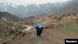 FILE - An Afghan man carries a ballot box on his back to polling stations which are not accessible by road in Shutul, Panjshir province, April 4, 2014. More than 100 people have died in avalanches in the region, local officials said, Feb. 25, 2015.