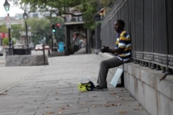 FILE - A street artist sings to no one along Jackson Square in the French Quarter of New Orleans, normally bustling with tourists, but now nearly deserted due to the new coronavirus pandemic, March 27, 2020.