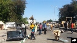 Petugas penyelamat membersihkan jalan menyusul bom mobil bunuh diri di sebuah pos militer di Maiduguri, Nigeria (14/1). (AP/Jossy Ola)