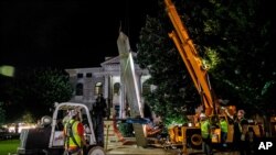 Workers remove a Confederate monument, June 18, 2020, in Decatur, Ga., the 30-foot obelisk in Decatur Square, erected by the United Daughters of the Confederacy in 1908, was ordered by a judge to be removed and placed into storage indefinitely.