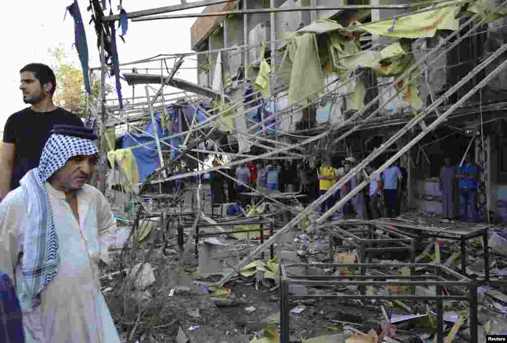 People gather at the site of a car bomb attack in Baghdad, October 21, 2014. 