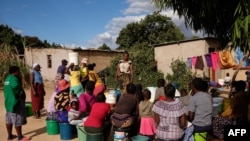 FILE - Letwin Mhande awaits her turn to load an allocation of four buckets of water per family per day at a community run borehole in Epworth, an informal settlement East of Harare, May 23 2024.