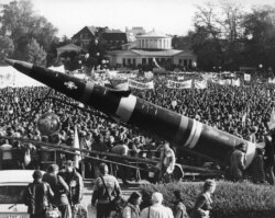 FILE - A life-size mockup of a Pershing II missile dwarfs the demonstrators protesting the scheduled deployment of missiles, in downtown Bonn, Germany, Oct. 22, 1983.
