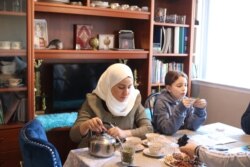 Syrian refugee Nawar Almadani sits with daughter Esraa, 10, as she plays a game. The family resettled in Chicago after living in Turkey for two years after the war in Syria broke out. (K. Khan/VOA)