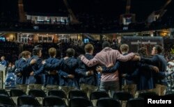 Mourners link arms during a memorial service for three slain University of Virginia football players Lavel Davis Jr., D’Sean Perry and Devin Chandler at John Paul Jones Arena on Nov. 19, 2022. (Erin Edgerton/Pool Photo-USA TODAY Sports via REUTERS)