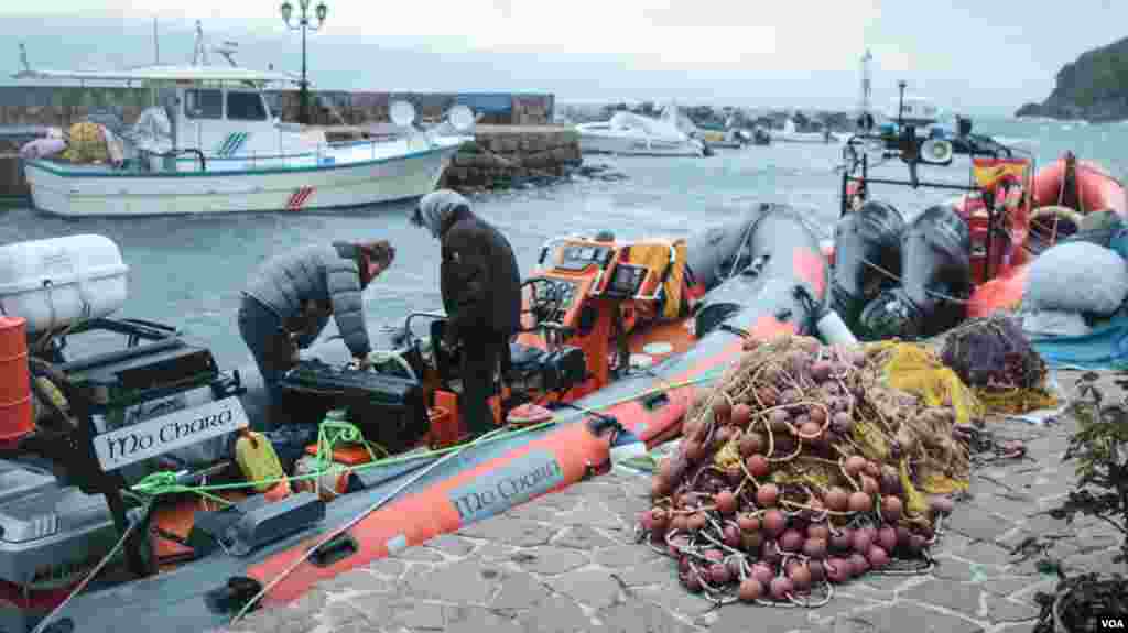 At the harbor in Skala Sikamineas on the Greek island of Lesvos, volunteers for the Refugee Rescue team carry out maintenance on their boat. (J. Owens/VOA)