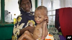 FILE - A malnourished five-year-old boy sits on his mother's lap at a hospital in Somalia, May 20, 2014. 