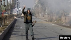 Seorang polisi Afghanistan memberikan komentar saat melihat asap akibat serangan di dekat konsulat Pakistan di Jalalabad, Afghanistan (13/1).