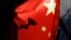 FILE - A surveillance camera is silhouetted behind a Chinese national flag in Beijing, China, Nov. 3, 2022.