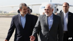 Menteri Luar Negeri Iran Mohammad Javad Zarif, tengah, berjalan bersama Duta Besar Iran untuk Irak Hassan Dannaie Fir, kiri, di bandara di Baghdad, Irak, 24 Agustus 2014.