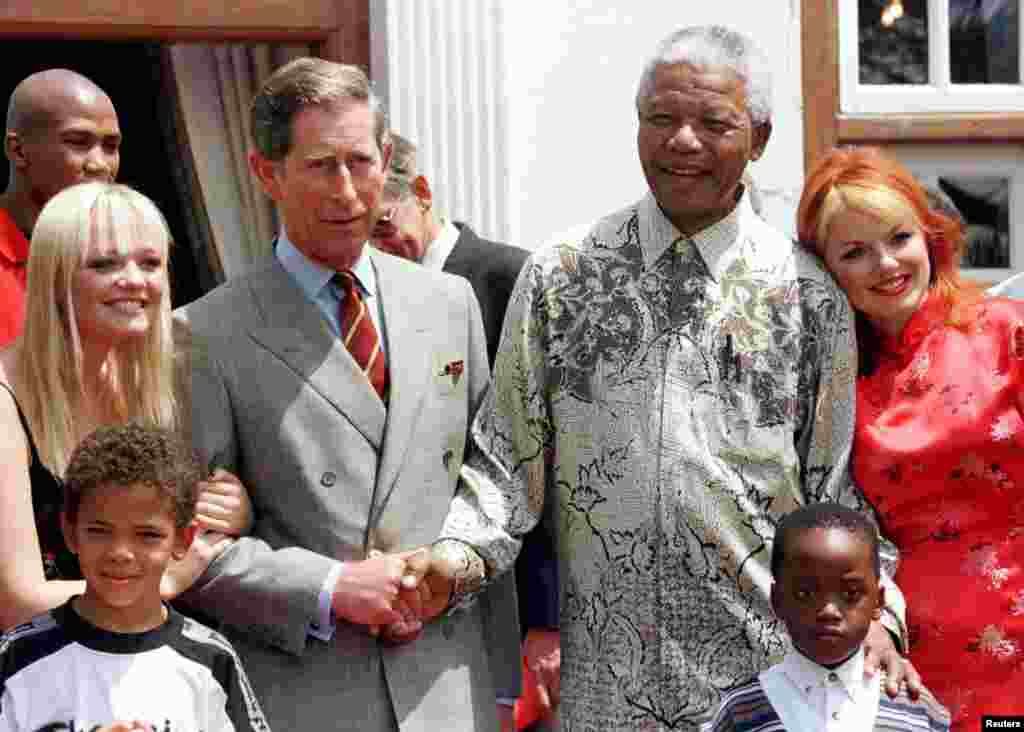 Presiden Nelson Mandela dan Pangeran Charles berjabat tangan, diapit dua personil Spice Girls, Emma (kiri) dan Gerri (kanan) di kediaman Mandela, 1 November 1997. 