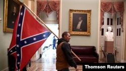 A supporter of President Donald Trump carries a Confederate battle flag on the second floor of the U.S. Capitol after breaching security, in Washington, Jan. 6, 2021.