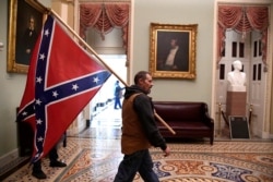 Seorang pendukung Presiden Donald Trump membawa bendera pertempuran Konfederasi di lantai dua Capitol AS setelah melanggar keamanan, di Washington, 6 Januari 2021. (Foto: Reuters)