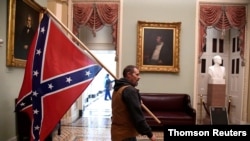 A supporter of President Donald Trump carries a Confederate battle flag on the second floor of the U.S. Capitol after breaching security, in Washington, Jan. 6, 2021.