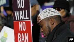 FILE - Abdirahman "OJ" Mohamed, of Seattle, holds a sign that reads "No Wall No Ban," during a protest against federal efforts to restrict immigration, Dec. 6, 2017, outside a federal courthouse in Seattle.
