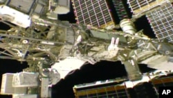 In this photo provided by NASA, NASA astronaut Anne McClain and Canadian astronaut David Saint-Jacques float outside the International Space Station, Monday, April 8, 2019, as they tackle battery and cable work.