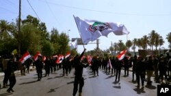 FILE - Iran-backed militia fighters march in central Baghdad, Iraq, June 29, 2021. Iraqi Shiite militias are showing a degree of defiance of their patron Iran by escalating rocket and drone attacks on the U.S. presence in the country.