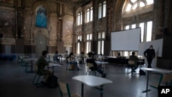 Siswa dan guru mereka mengenakan masker dan menjaga jarak satu sama lain di sekolah Royal Atheneum, di Antwerpen, Belgia, Senin, 18 Mei 2020.