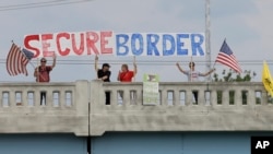 FILE - Demonstrators with signs on an overpass in Indianapolis, Indiana, protest against people who immigrate illegally.