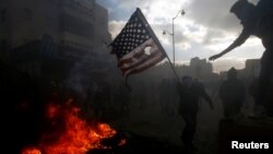 აქციის პალესტინელი მონაწილე ამერიკის დროშის დაწვას ცდილობს