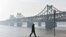 FILE - A man walks near the Friendship Bridge which spans the Yalu River between China and North Korea, in the Chinese border city of Dandong, in China's northeast Liaoning province, Feb. 22, 2019. 