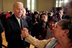 Democratic presidential candidate former Vice President Joe Biden holds a woman's hand while speaking to her at a campaign event, Feb. 5, 2020, in Somersworth, N.H.