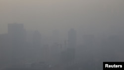 Sebuah konstruksi bangunan di Beijing terlihat berselimut kabut akibat polusi udara, 16 Desember 2016. (Foto: dok). Pada hari tersebut, pihak berwenang China mengeluarkan peringatan merah sebagai tanda tingkat bahaya pencemaran udara akibat terpapar polusi bagi masyarakat di kawasan itu.