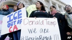 Protesters hold signs as they listen to speakers at a rally outside City Hall in San Francisco, Jan. 25, 2017.