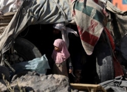 A girl stands outside her family's hut at a camp for internally displaced people on the outskirts of Sanaa, Yemen, March 1, 2021.