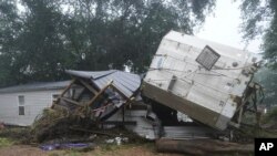 Sebuah rumah mobil dan sebuah truk trailer terlihat berada di dekat sungai Minggu, 22 Agustus 2021, setelahhanyut oleh air banjir sehari sebelumnya di Tennessee. (Foto: AP)