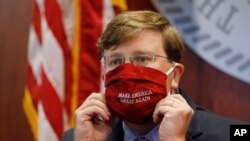 Mississippi Gov. Tate Reeves adjusts his "Make America Great Again," face mask upon concluding his press briefing with members of the state's COVID-19 response team, to discuss the ongoing strategy to reduce and limit transmission, Monday, July 20,…