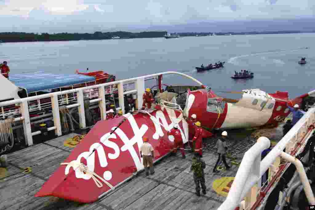 Crew members of Crest Onyx ship prepare to unload parts of AirAsia Flight 8501 from a ship at Kumai port in Pangkalan Bun, Sunday, Jan.11, 2015.