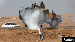 A protester throws stones at an armored army vehicle during a pro-Kurdish demonstration in solidarity with people of Kobani, near the Mursitpinar border crossing on the Turkish-Syrian border, in the Turkish town of Suruc in southeastern Sanliurfa province