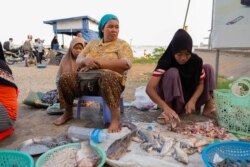 Khmer Islam fish seller Sos Nob, 48, sits beside her niece in front of the Sokha ferry entrance on the evening of Oct. 14, 2019 in Phnom Penh, Cambodia. (Malis Tum/VOA Khmer)