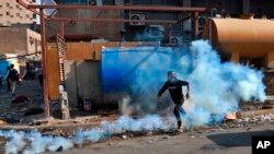 Seorang pengunjuk rasa anti-pemerintah diatasi dengan gas air mata yang ditembakkan oleh polisi anti huru hara selama bentrokan, di Khilani Square, Baghdad, Irak, Rabu, 13 November 2019. (Foto: AP/Khalid Mohammed)