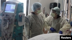 រូបឯកសារ៖ គិលានុបដ្ឋាក ពិនិត្យមើល​អ្នកជំងឺ​ដែល​ស្ថិត​ក្នុង​មណ្ឌល​ថែទាំ​អ្នកជំងឺ​កូវីដ១៩​កម្រិត​ធ្ងន់ នៅ​រដ្ឋ California នៅ​ថ្ងៃទី១៩ ខែវិច្ឆិកា ឆ្នាំ២០២០។