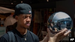 FILE - Carlos Jose, 21, has his eyes scanned by an orb, at a Worldcoin registration point in Barcelona, Spain, on Friday, Aug. 4, 2023. (AP Photo/Emilio Morenatti)