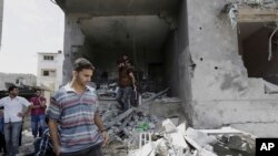 Warga Palestina mengamati rumah kepala polisi Gaza Tasyir al-Batsh yang hancur setelah terkena serangan rudal Israel hari Sabtu (12/7), menewaskan setidaknya 18 orang, di Gaza, 13 Juli 2014. 