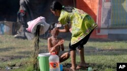 A woman bathes a child at a temporary shelter in Palu, Central Sulawesi, Indonesia, Oct. 4, 2018, after parts of the province were hit by a powerful earthquake and tsunami.