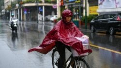 ស្ត្រី​ម្នាក់​ពាក់​អាវ​ភ្លៀង​ជិះ​កង់​ពេល​ភ្លៀង​ធ្លាក់​នៅ​ក្រុង​ហាណូយ ថ្ងៃទី១៤ ខែតុលា ឆ្នាំ២០២០ ខណៈ​ដែល​ព្យុះ​ត្រូពិច Nangka ធ្វើ​ឲ្យ​បាក់ដី​នៅ​ភាគ​កណ្ដាល​វៀតណាម។