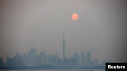 The sun rises through a cover of wildfire smoke above the CN Tower and downtown skyline in Toronto, Ontario, Canada July 20, 2021. 