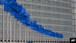 FILE - Workers adjust the EU flags in front of EU headquarters in Brussels, Belgium, June 22, 2016. 