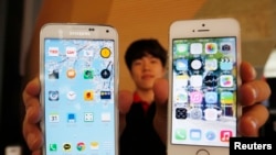 Seorang penjual HP menunjukkan Galaxy 5 Samsung Electronics (kiri) dan iPhone 5 and Apple Inc (kanan) di sebuah toko di Seoul, 16 Juli 2014. 