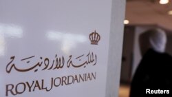 纽约肯尼迪国际机场内一名旅客走过皇家约旦航空公司标志牌。（资料照片）