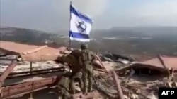 Tangkapan layar video yang beredar ri sosial media tampak sejumlah tentara Israel mengibarkan bendera Israel di Desa Maroun al-Ras, di selatan Lebanon, delat pos Pasukan Perdamaian PBB untuk Lebanon (UNIFIL), 8 Oktober 2024. (Foto: UGC/AFP)